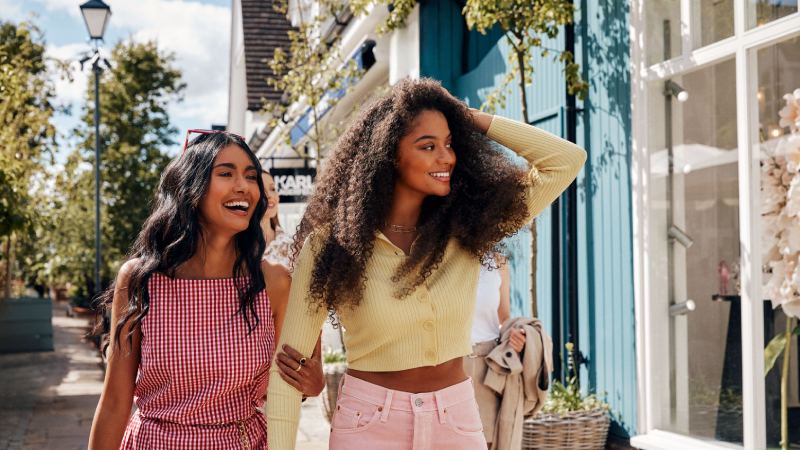 Two young joyful women walking around a Bicester village