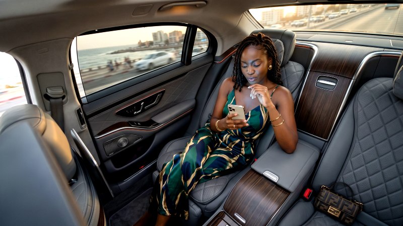 Traveler using a smartphone in a luxury car