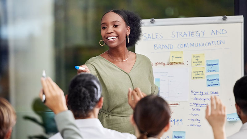 A woman leads a discussion and debate on ideas, people raise their hands